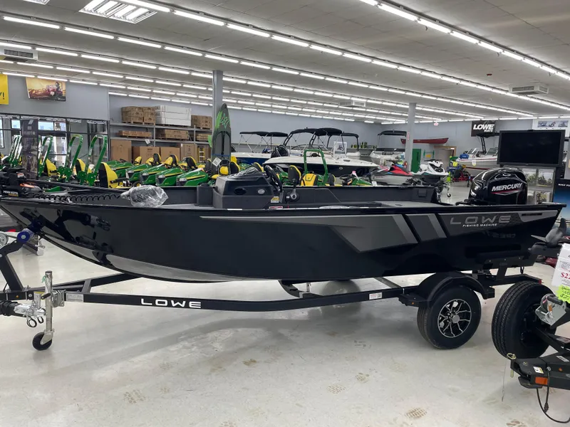Slide: The Image of 2025 Lowe FM1675S fishing boat on display in showroom with trailer. - 3