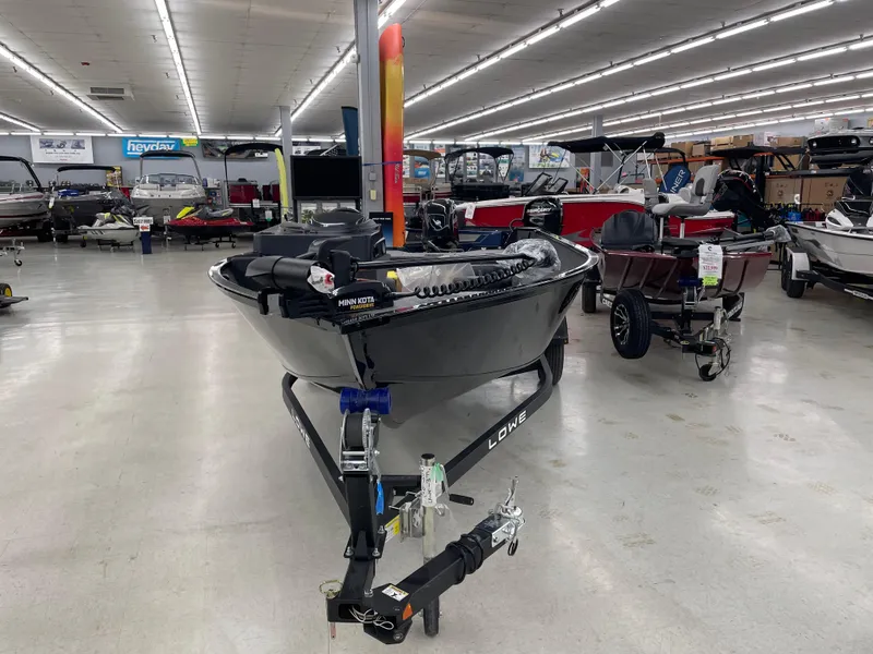 Slide: The Image of 2025 Lowe FM1675S fishing boat displayed in a showroom with various other boats. - 7