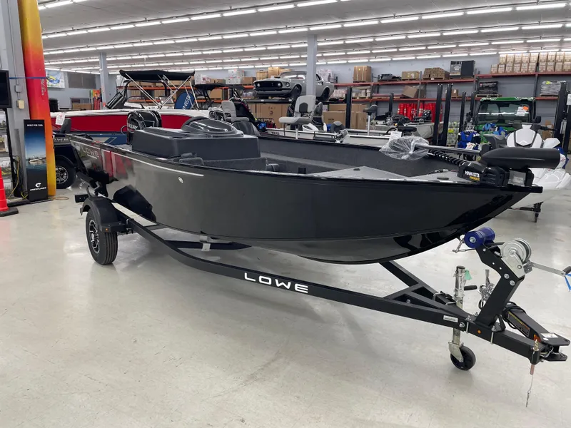 Slide: The Image of 2025 Lowe FM1675S boat on trailer in showroom, featuring sleek black design. - 8