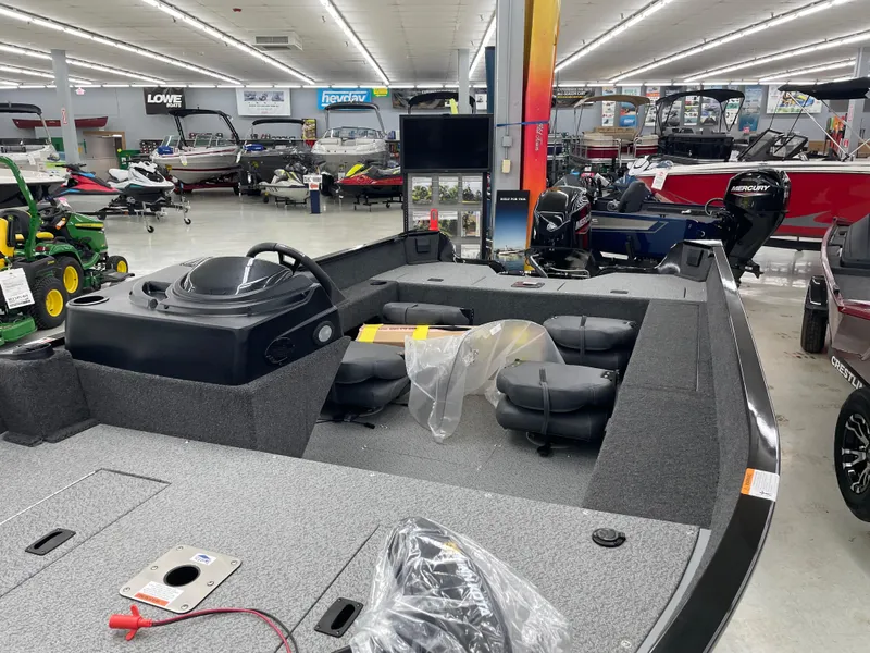 Slide: The Image of 2025 Lowe FM1675S boat displayed in a showroom with various other boats and equipment. - 9