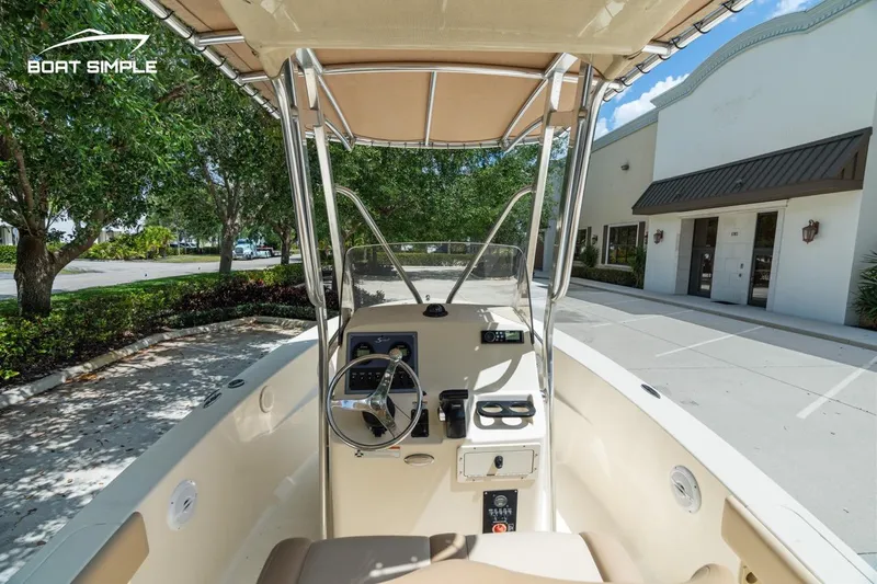 Slide: The Image of 2022 Scout 195 Sportfish boat interior with steering wheel and controls, parked near a building. - 11