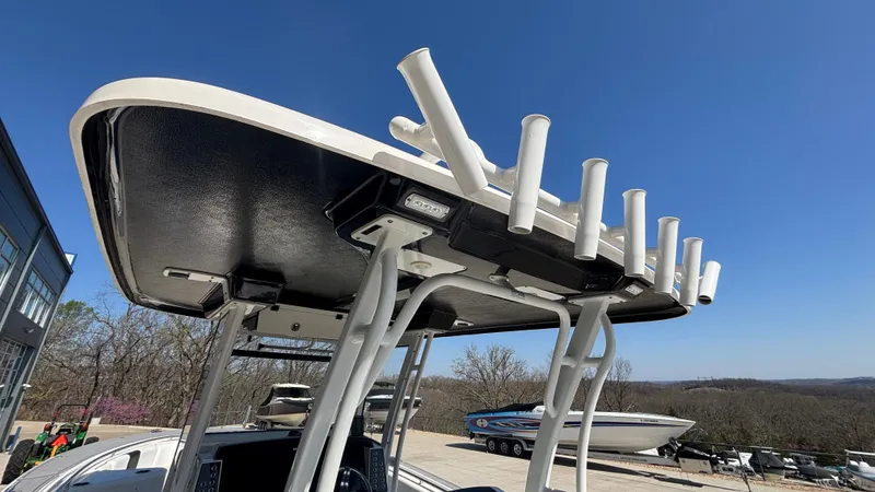 Slide: The Image of 2021 Robalo R302 CC boat with rod holders and T-top, parked outdoors. - 14