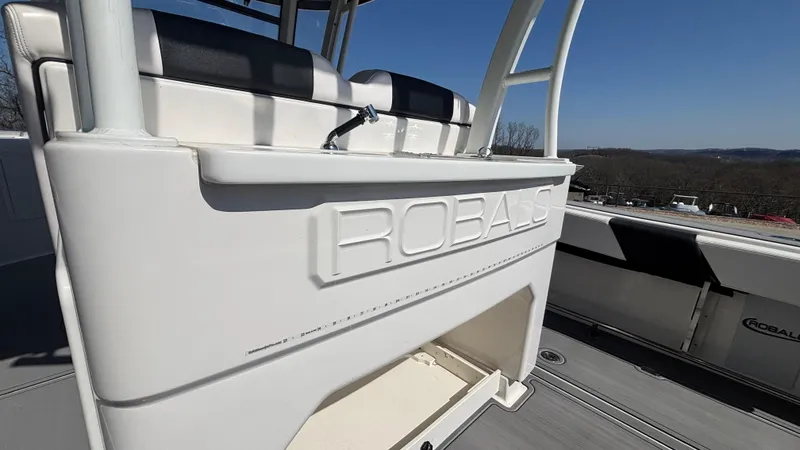 Slide: The Image of 2021 Robalo R302 CC boat interior, featuring seating and storage, under clear blue sky. - 17