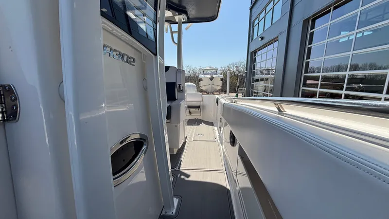 Slide: The Image of 2021 Robalo R302 CC boat side view, docked near a modern building. - 26