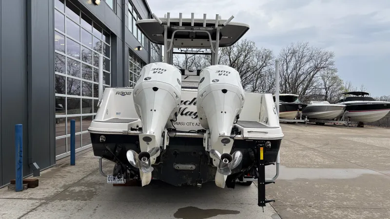 Slide: The Image of 2021 Robalo R302 CC boat with dual outboard engines, parked near a building. - 3