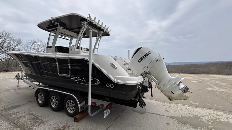 Slide: The Image of 2021 Robalo R302 CC boat on trailer with Yamaha outboard motor, parked outdoors. - 4
