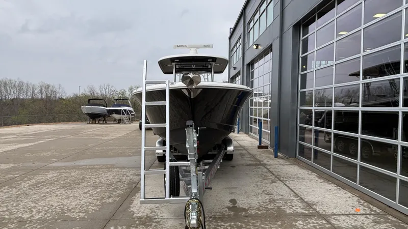 Slide: The Image of 2021 Robalo R302 CC boat on trailer outside a modern building. - 5
