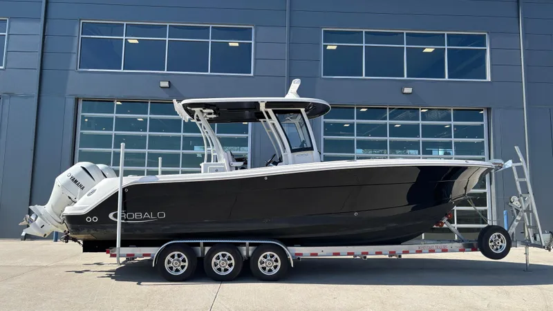 Slide: The Image of 2021 Robalo R302 CC boat on trailer, parked outside a building. - 7