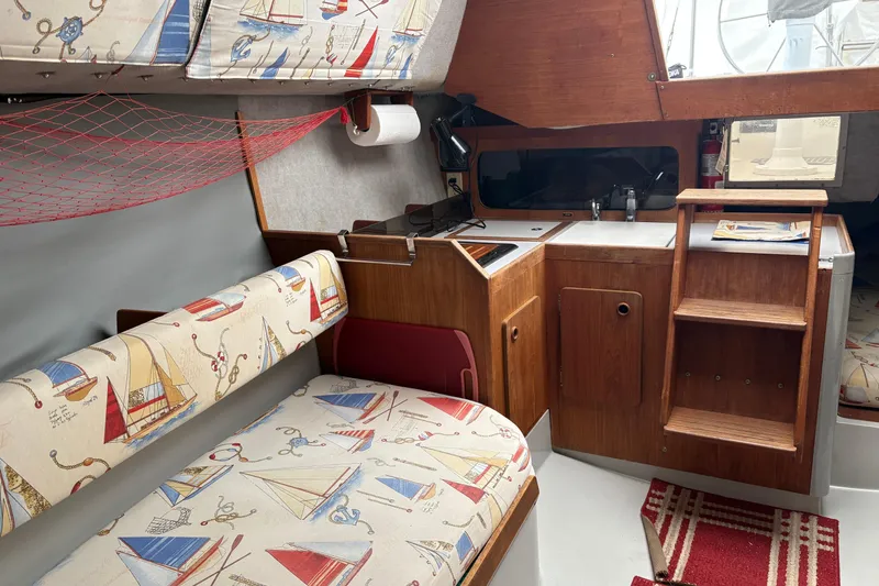 Slide: The Image of Interior of a 1989 O'Day 272 sailboat with nautical-themed upholstery and compact kitchen area. - 11