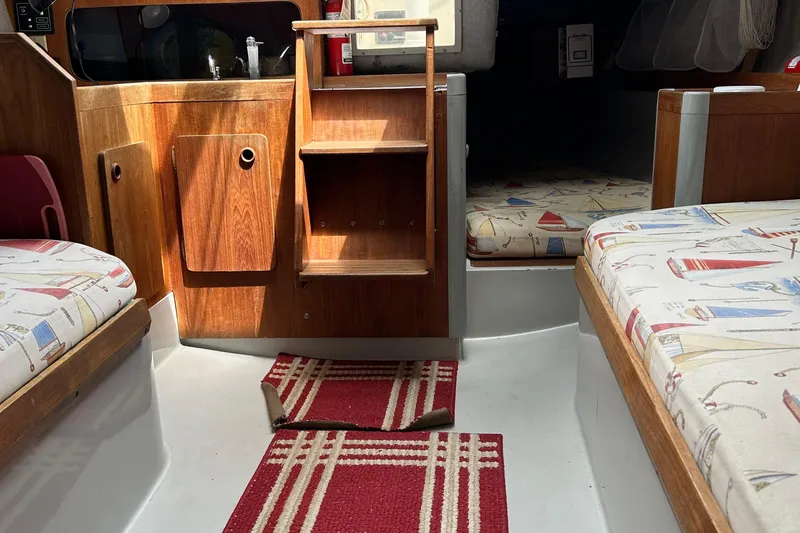 Slide: The Image of Interior of a 1989 O'Day 272 sailboat with wooden cabinetry and nautical-themed cushions. - 15