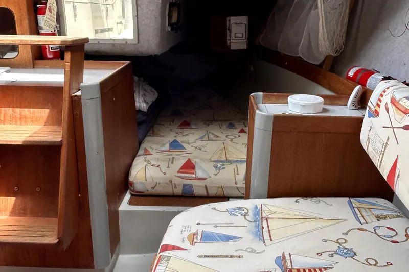 Slide: The Image of Interior of a 1989 O'Day 272 sailboat with nautical-themed cushions and wooden accents. - 16