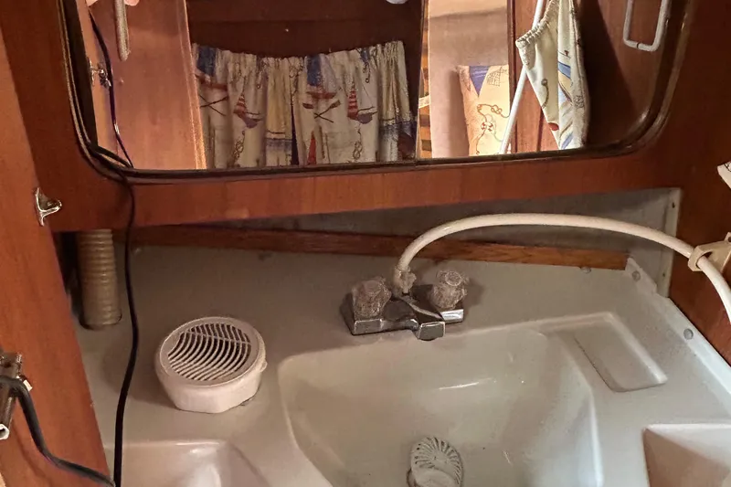 Slide: The Image of 1989 O'Day 272 sailboat interior with sink, faucet, and nautical-themed curtains. - 18