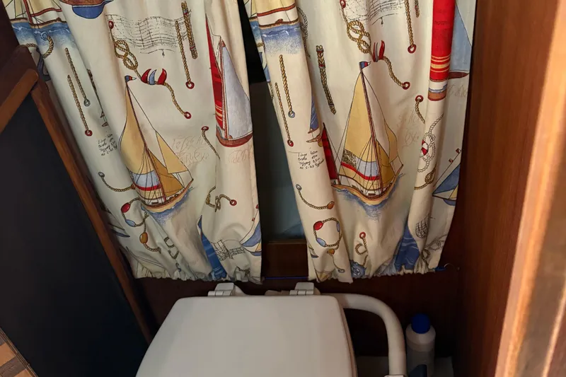 Slide: The Image of 1989 O'Day 272 boat interior with nautical-themed curtains and a compact toilet. - 19