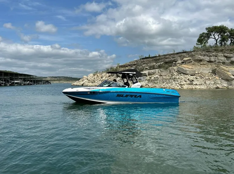 Slide: The Image of 2017 Supra SE 550 boat on calm water near rocky shoreline under cloudy sky. - 10