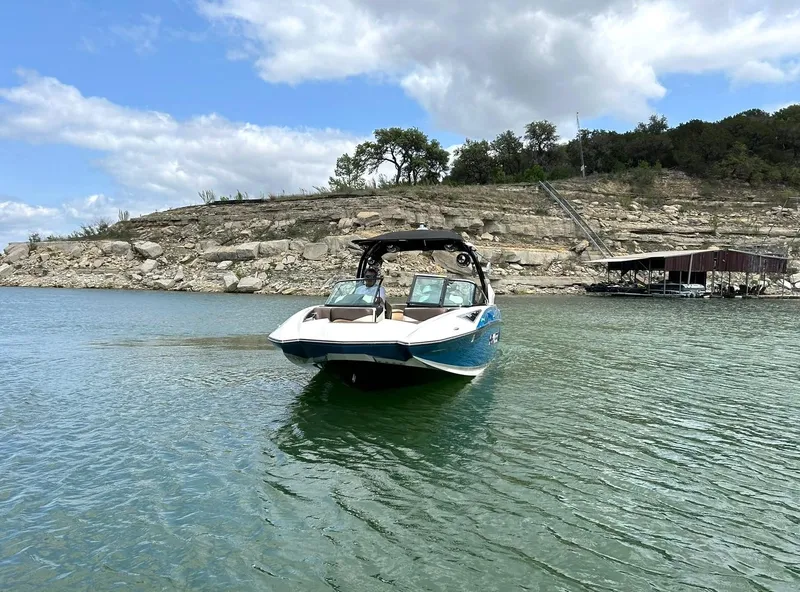 Slide: The Image of 2017 Supra SE 550 boat on a serene lake with rocky shoreline backdrop. - 13