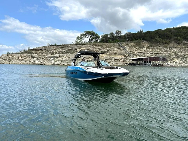 Slide: The Image of 2017 Supra SE 550 boat cruising on a lake with rocky shoreline and cloudy sky. - 15