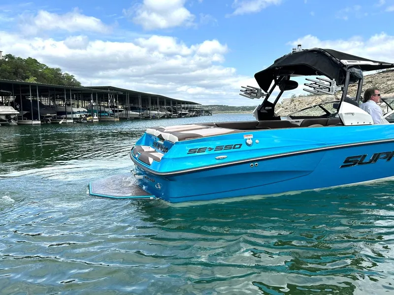 Slide: The Image of 2017 Supra SE 550 boat on a lake, with docks and trees in the background. - 17