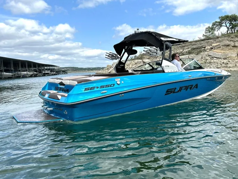 Slide: The Image of 2017 Supra SE 550 boat on a lake with clear skies and rocky shoreline. - 18