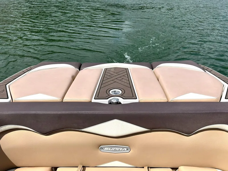 Slide: The Image of 2017 Supra SE 550 boat interior with tan and brown upholstery on a lake. - 22