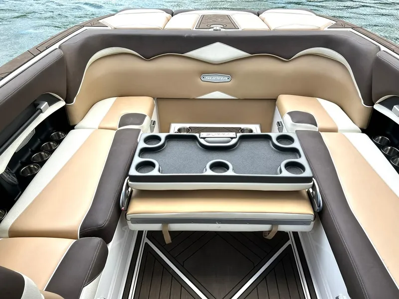 Slide: The Image of 2017 Supra SE 550 boat interior with beige and brown seating, cup holders, and a table. - 29