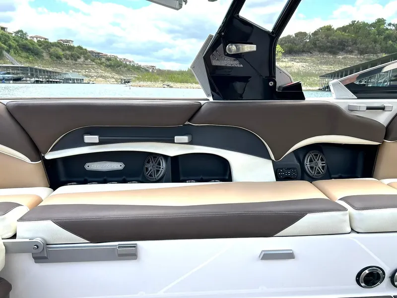 Slide: The Image of 2017 Supra SE 550 boat interior with brown and beige seating, speakers, and scenic lake view. - 32