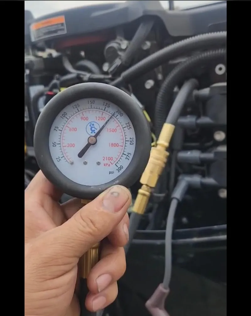 Slide: The Image of Hand holding a pressure gauge near a 2022 Lowe Skorpion 17 engine. - 45