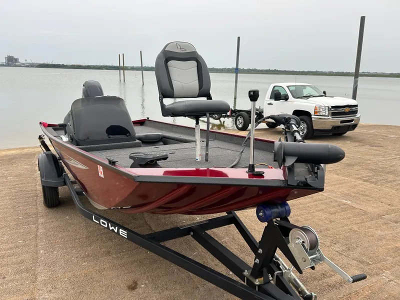 Slide: The Image of 2022 Lowe Skorpion 17 boat on trailer by lake, with pickup truck in background. - 6