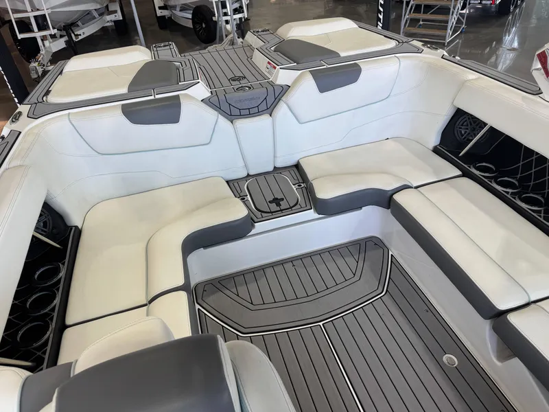 Slide: The Image of 2019 Nautique Super Air Nautique GS22 interior with white and gray seating, cup holders, and deck flooring. - 14