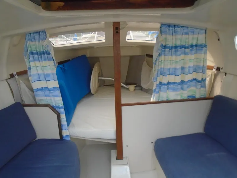 Slide: The Image of Interior of a 1996 Hunter 23.5 sailboat with blue seating and striped curtains. - 3