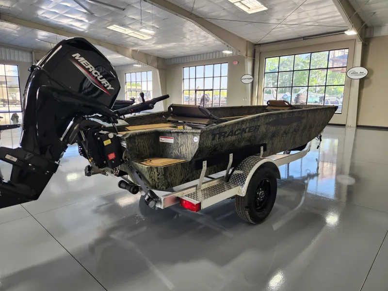Slide: The Image of 2025 Tracker Grizzly 1650 T Prairie Wings Edition boat in showroom, featuring Mercury outboard motor. - 4