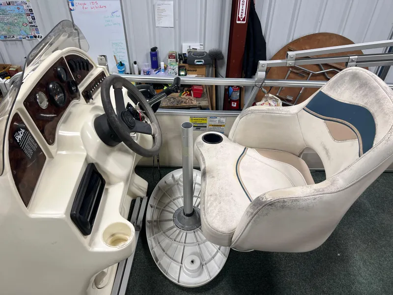 Slide: The Image of Captain's chair and dashboard of a 2008 Sweetwater 2386 RE boat in a workshop setting. - 12