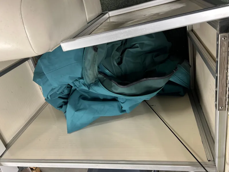 Slide: The Image of Storage compartment with teal fabric inside a 2008 Sweetwater 2386 RE boat. - 19