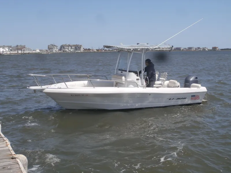 Slide: The Image of 2007 Triumph 21 Center Console boat on water, with person steering near dock. - 2