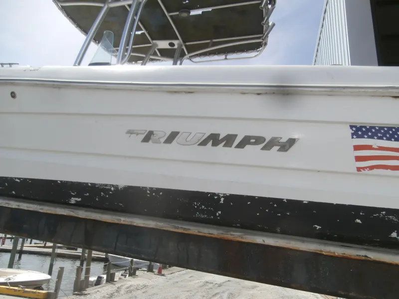 Slide: The Image of 2007 Triumph 21 Center Console boat with American flag decal, docked outdoors. - 9