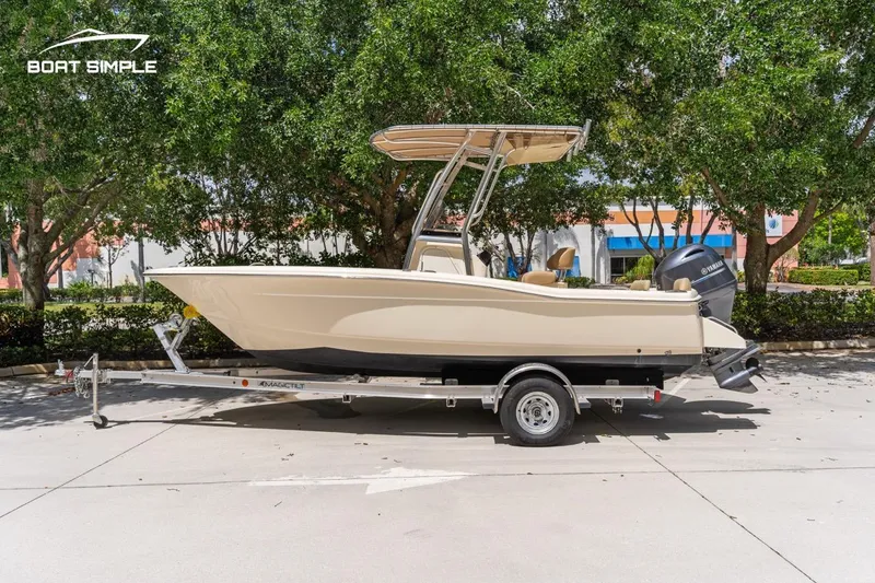 Slide: The Image of 2022 Scout 195 Sportfish boat on trailer, parked outdoors with trees in the background. - 4