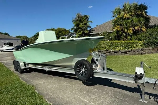 Slide: The Image of Custom Vernese V23 boat on trailer, parked on driveway, surrounded by greenery. - 16