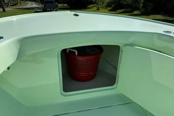 Slide: The Image of Open storage compartment on a 2021 Custom Vernese V23 boat with a red basket inside. - 25