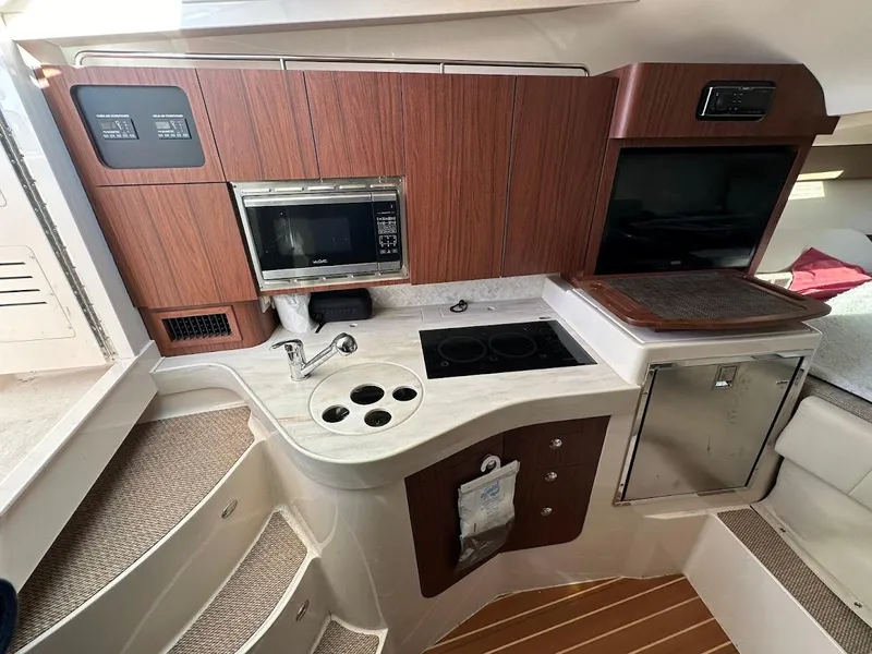 Slide: The Image of 2022 Grady-White Express 330 boat kitchen with microwave, stove, and wooden cabinetry. - 31
