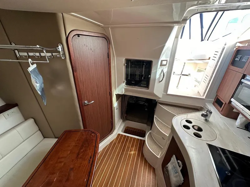 Slide: The Image of 2022 Grady-White Express 330 cabin interior with kitchenette, seating, and wooden flooring. - 34