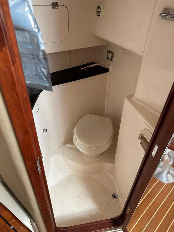 Slide: The Image of 2022 Grady-White Express 330 boat bathroom interior with compact toilet and wooden accents. - 35