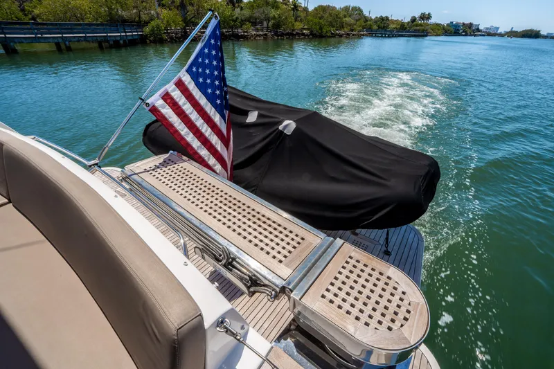 Slide: The Image of American flag on 2012 Prestige 500 Fly yacht, cruising on a serene waterway. - 11