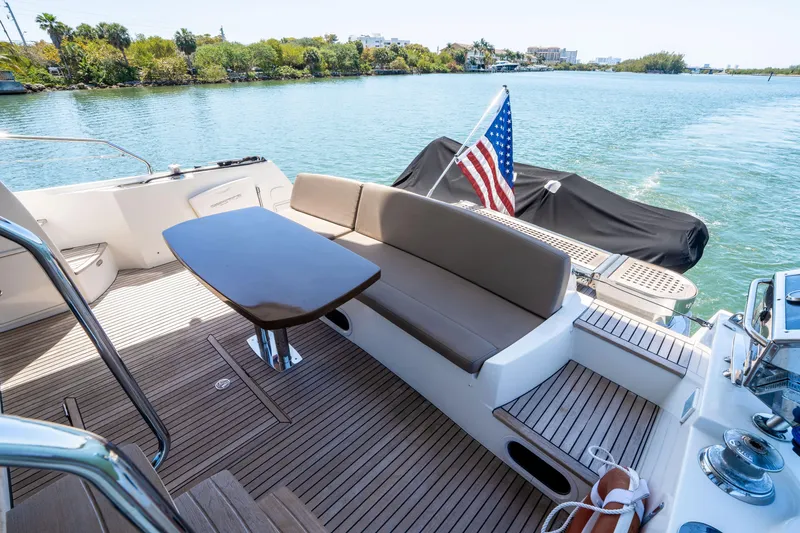 Slide: The Image of Prestige 500 Fly 2012 yacht deck with seating, table, and American flag on calm water. - 14