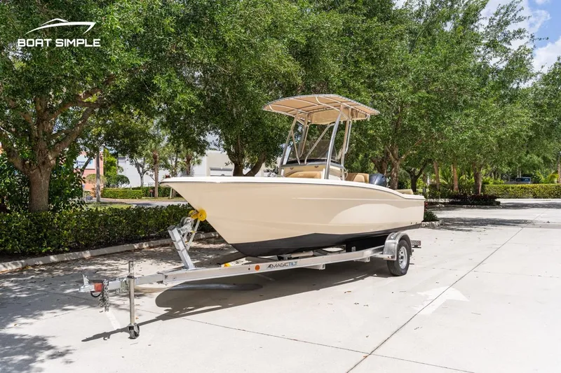 Slide: The Image of 2022 Scout 195 Sportfish boat on trailer, parked outdoors with trees in the background. - 7
