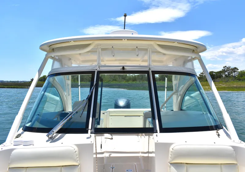 Slide: The Image of 2012 Pursuit DC 265 Dual Console boat on water, clear sky background. - 10