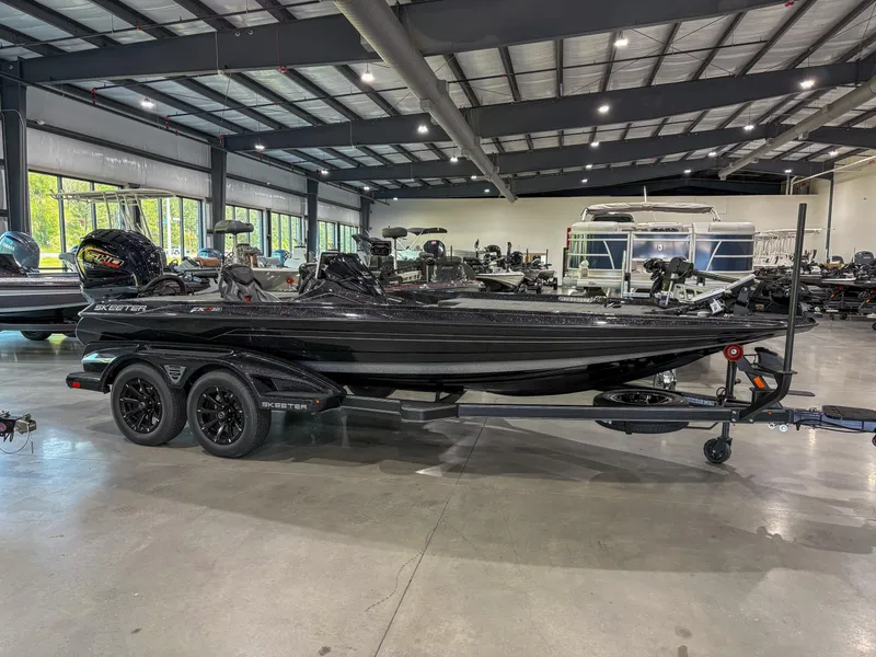 Slide: The Image of 2025 Skeeter FXR 20 boat in showroom, sleek black design, dual-axle trailer. - 6