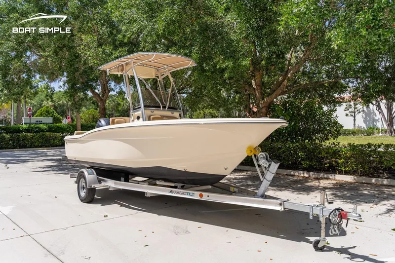 Slide: The Image of 2022 Scout 195 Sportfish boat on trailer, parked outdoors under trees. - 1