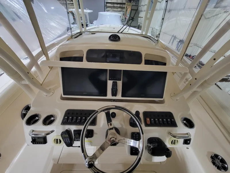 Slide: The Image of 2019 Grady-White Canyon 336 helm with dual screens and steering wheel in a boat garage. - 19