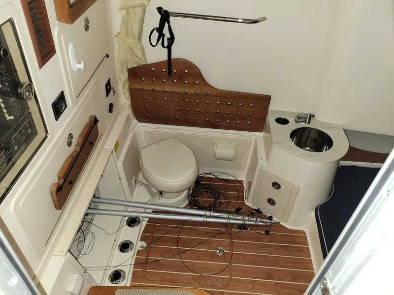 Slide: The Image of 2019 Grady-White Canyon 336 boat interior with toilet, sink, and fishing rods. - 33