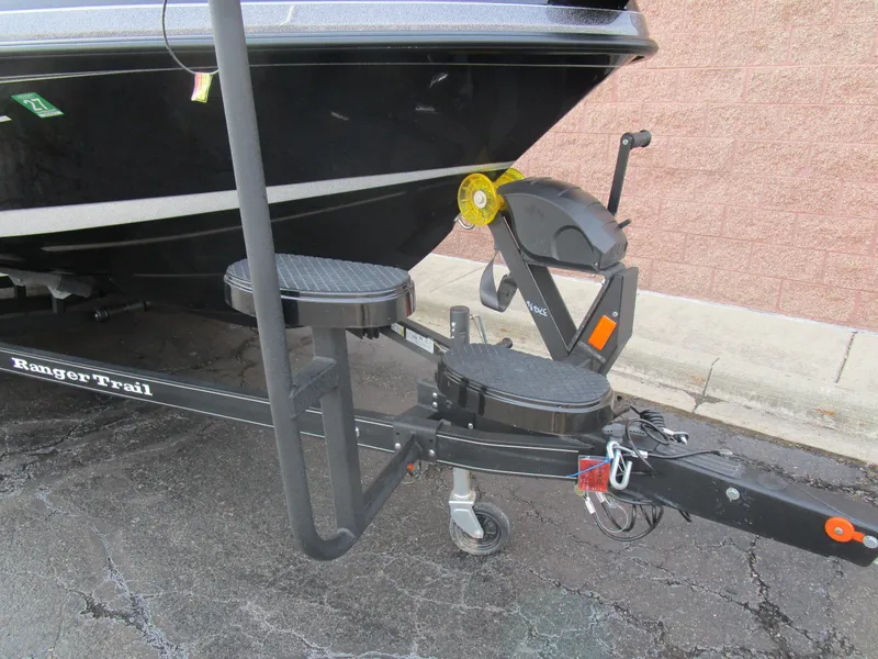 Slide: The Image of 2024 Ranger 621 CUP boat trailer with step ladder and winch, parked on asphalt. - 10