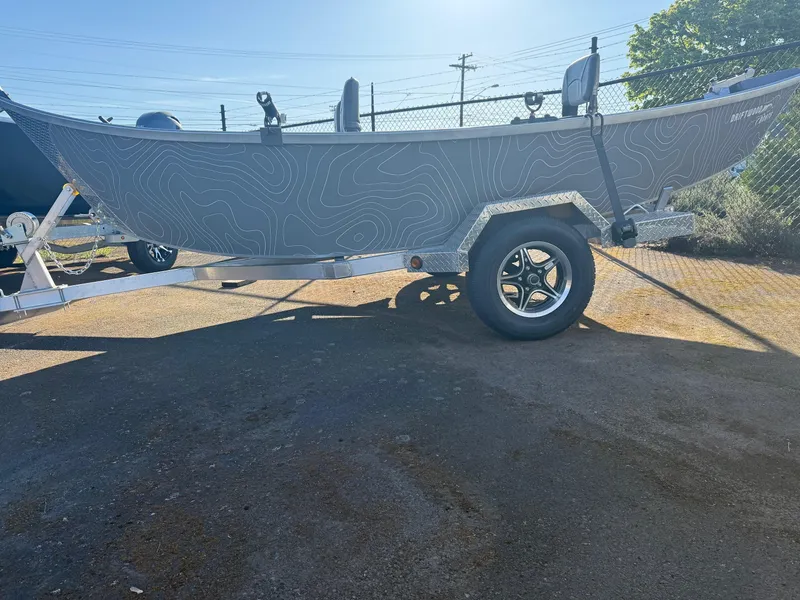 Slide: The Image of 2025 Driftwood Boats Drifter 18.5 on trailer, featuring sleek design and topographic pattern. - 2
